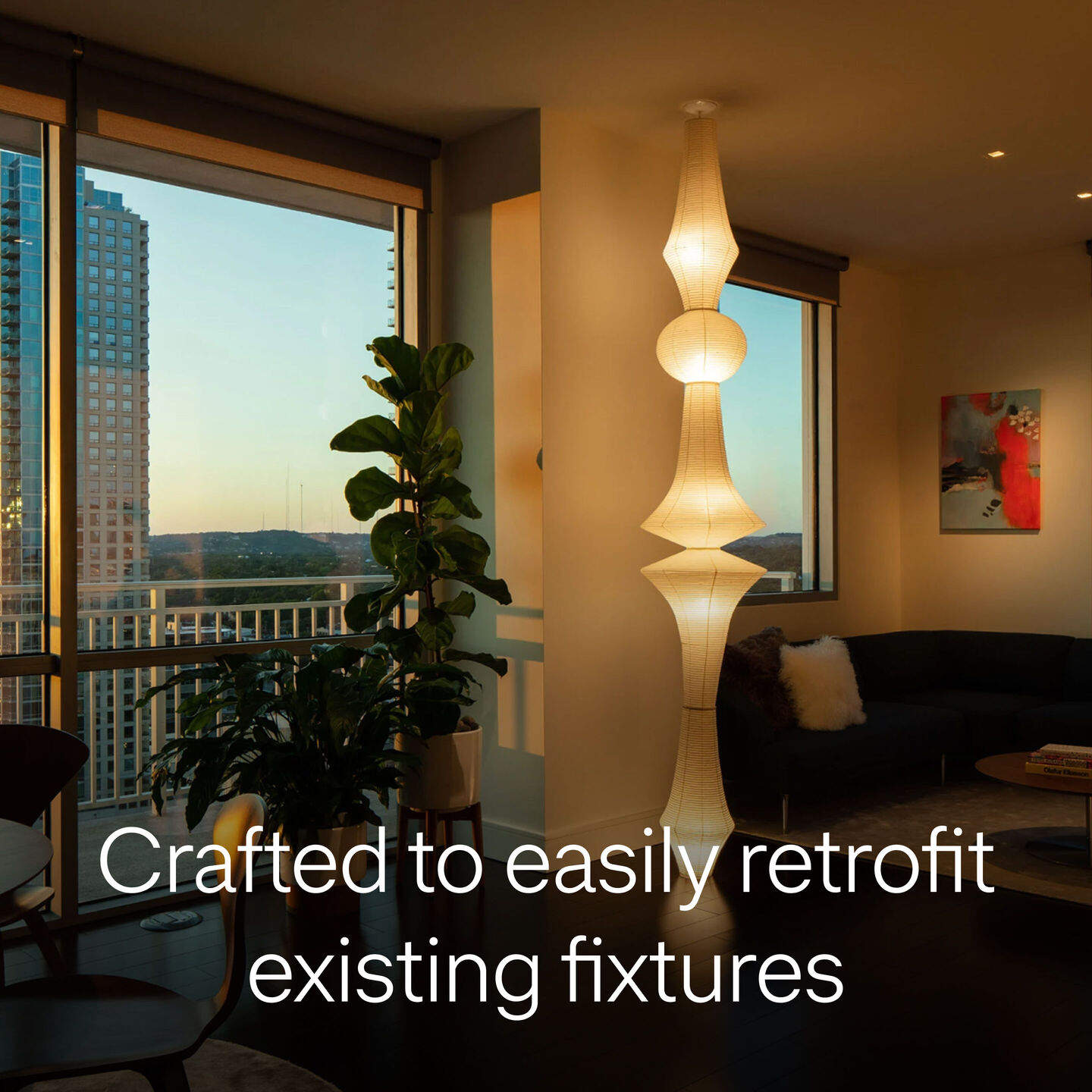 Warm-toned apartment interior at sunset with layered lighting and a statement pendant, labeled “Crafted to easily retrofit existing fixtures”