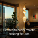 Warm-toned apartment interior at sunset with layered lighting and a statement pendant, labeled “Crafted to easily retrofit existing fixtures”