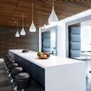 Contemporary kitchen illuminated by sleek pendant lights over island with complementary ambient and task lighting throughout